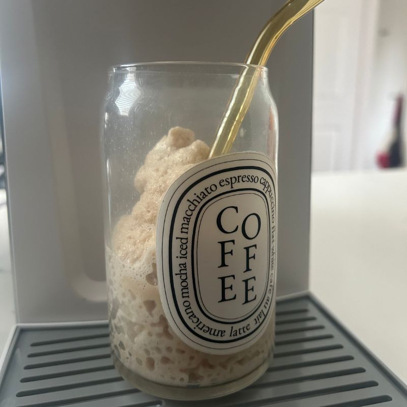 Frappucino made in ice cream maker machine sitting on the drip tray with a straw