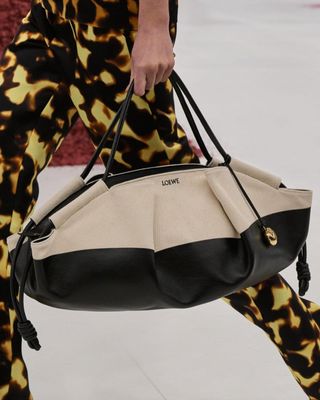 close-up shot of Loewe model holding black-and-white Paseo bag on the runway