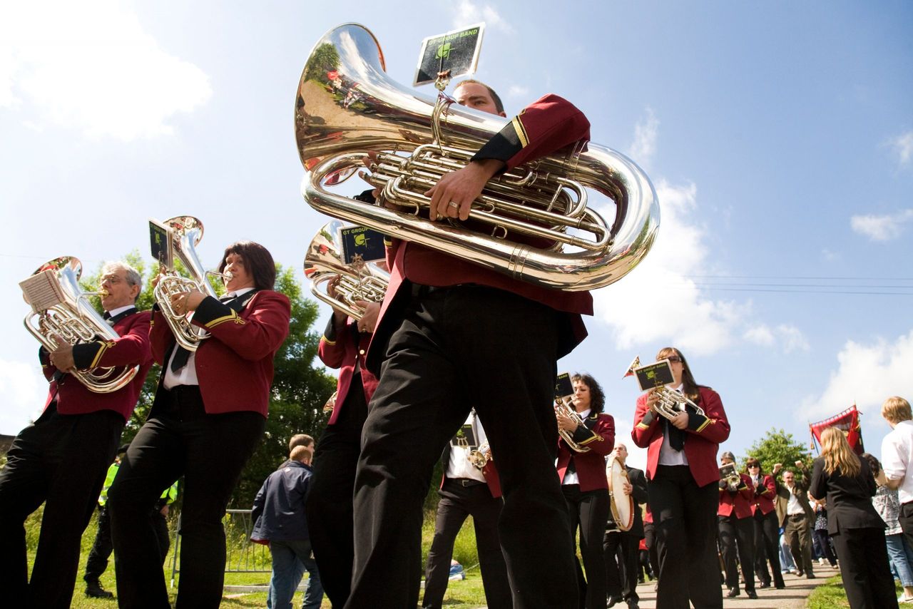 A brass band marches ahead of a colliery banner