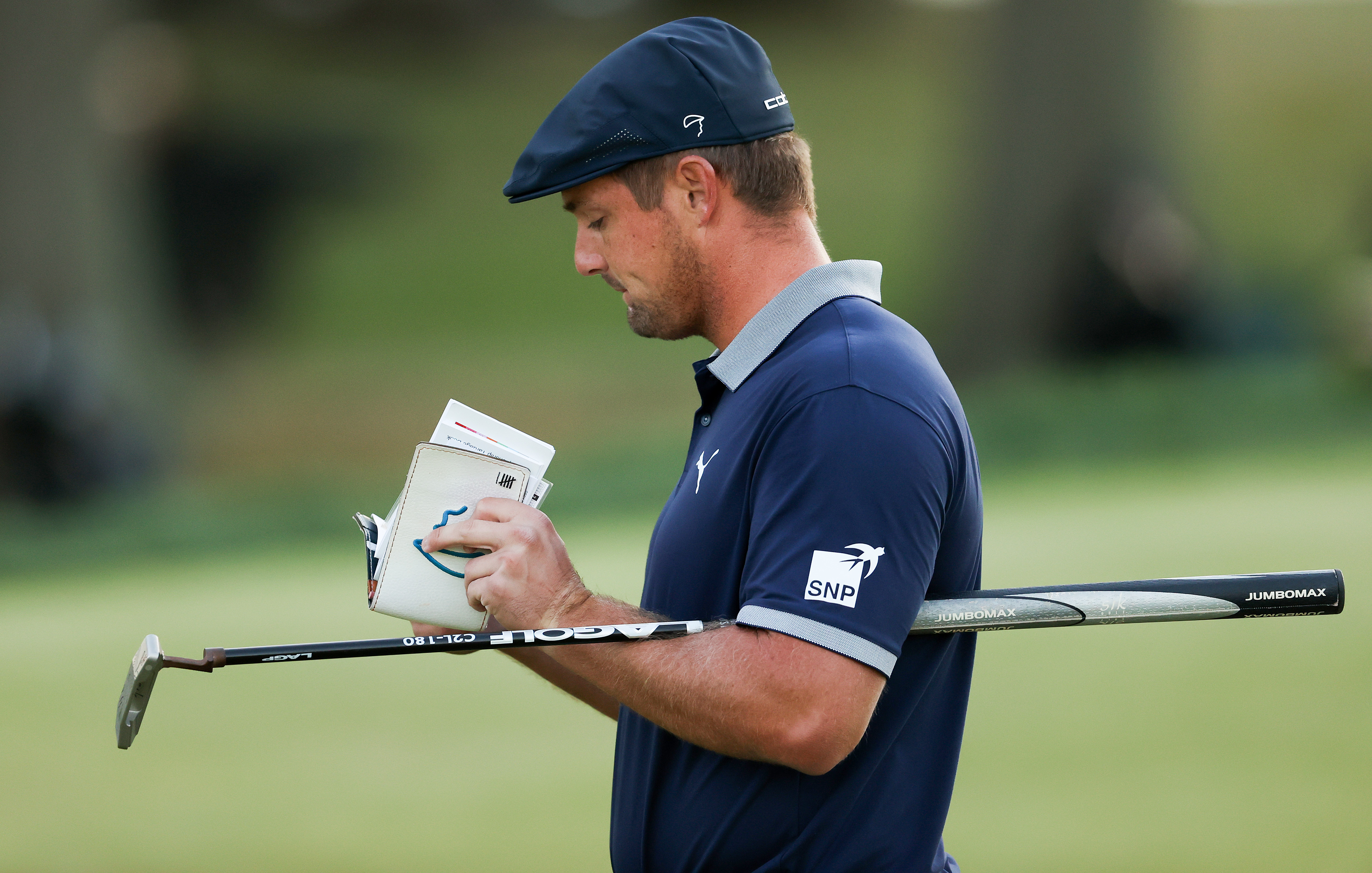 Bryson DeChambeau looks at a yardage book