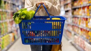 A woman carries a full shopping basket