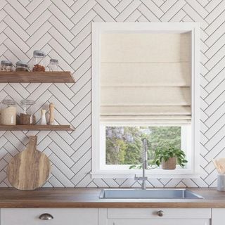 A kitchen with white tile and beige Roman shades