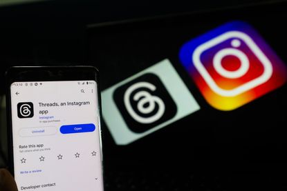 A photo of the Threads app in front of a Thread logo and an Instagram logo