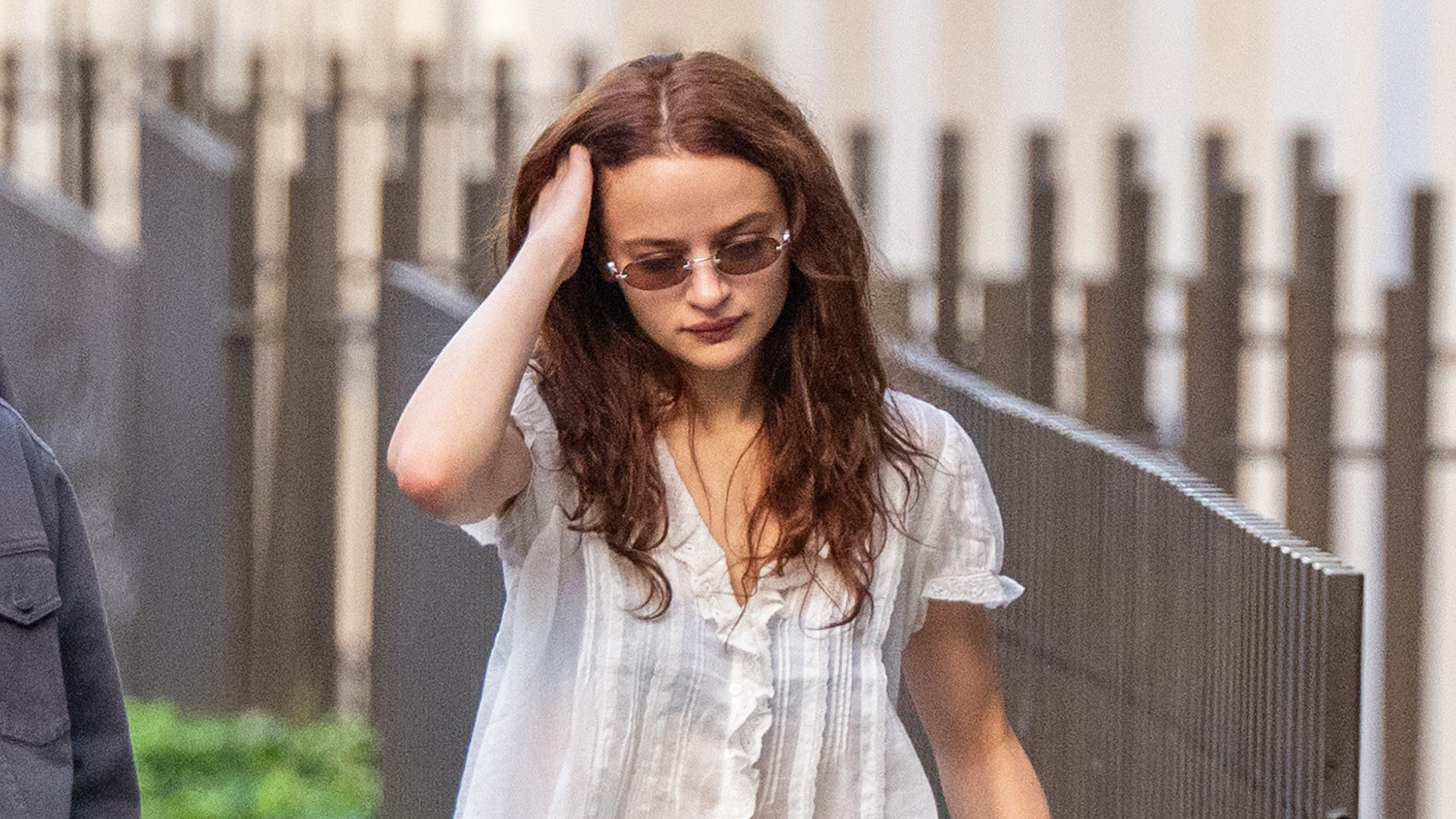 Joey King wearing white ruffle top, jeans, and sandals