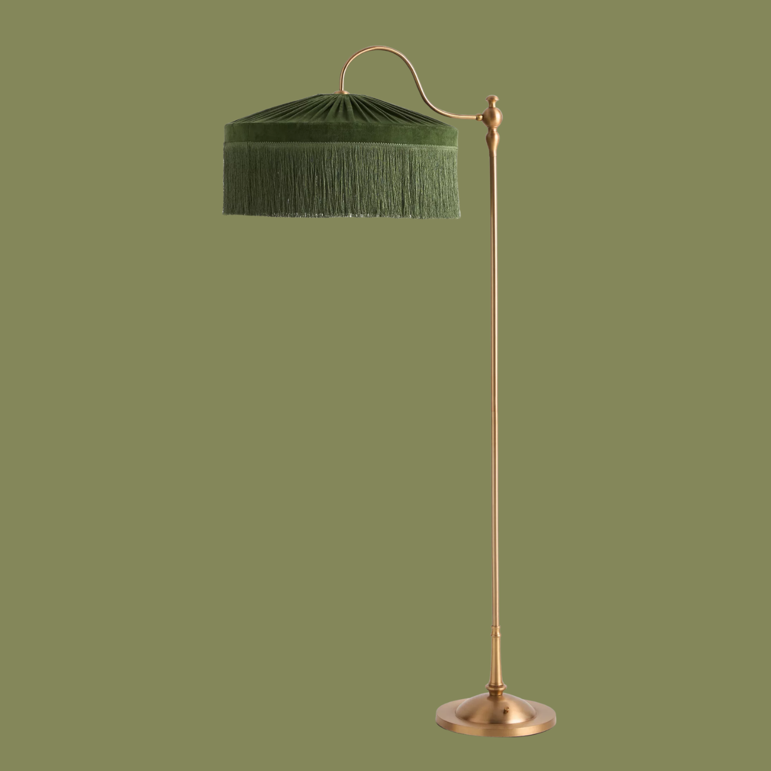 A brass floor lamp with a green fringe shade