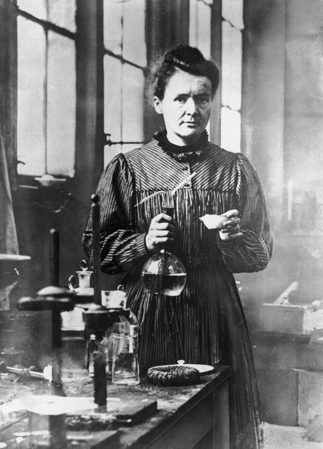 Marie Curie poses with scientific equipment in a lab