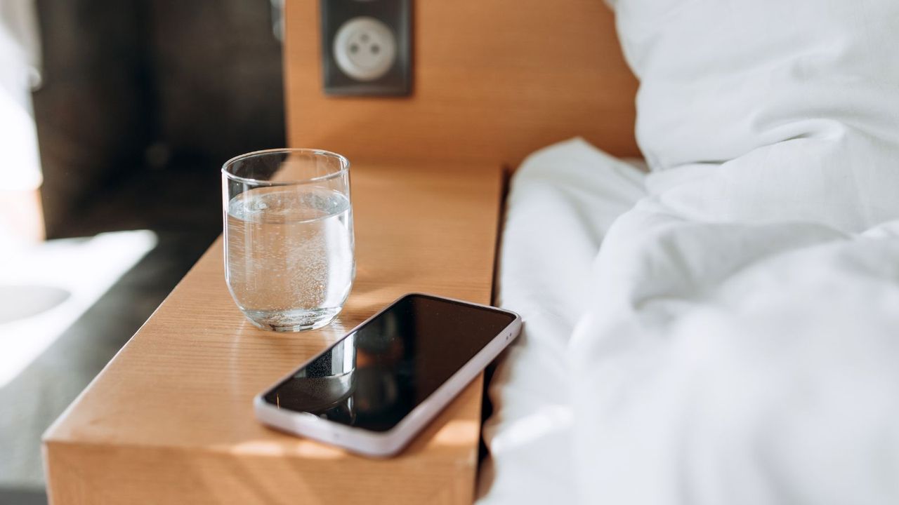 Glass of water and smart phone on wooden table bokeh background. 