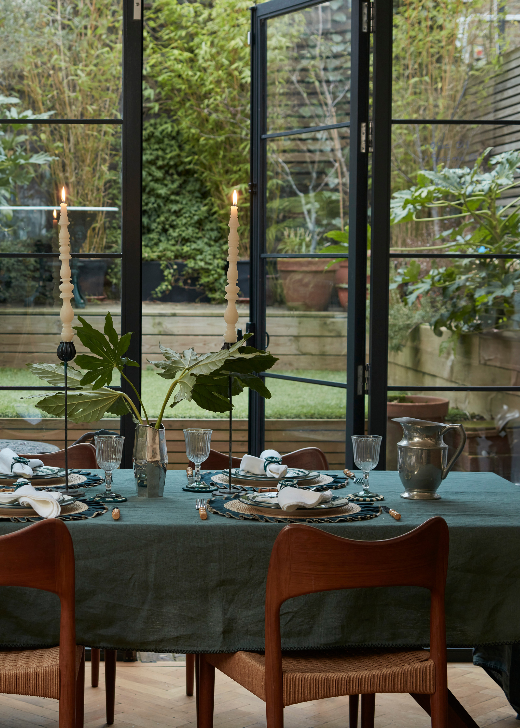 A cool, earthy dinner party set indoors by a garden space