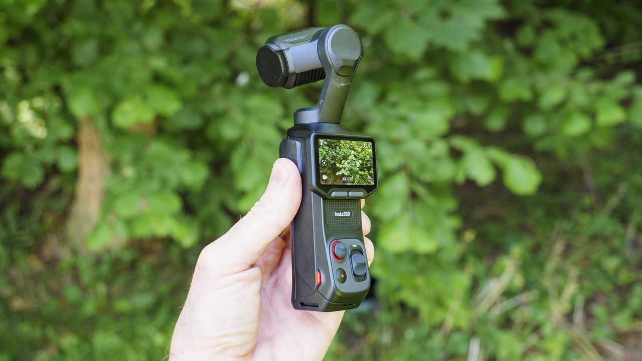 Insta360 Luna Ultra vlogging camera in person's hand, screen rotated and 4K 60p video active, leafy background
