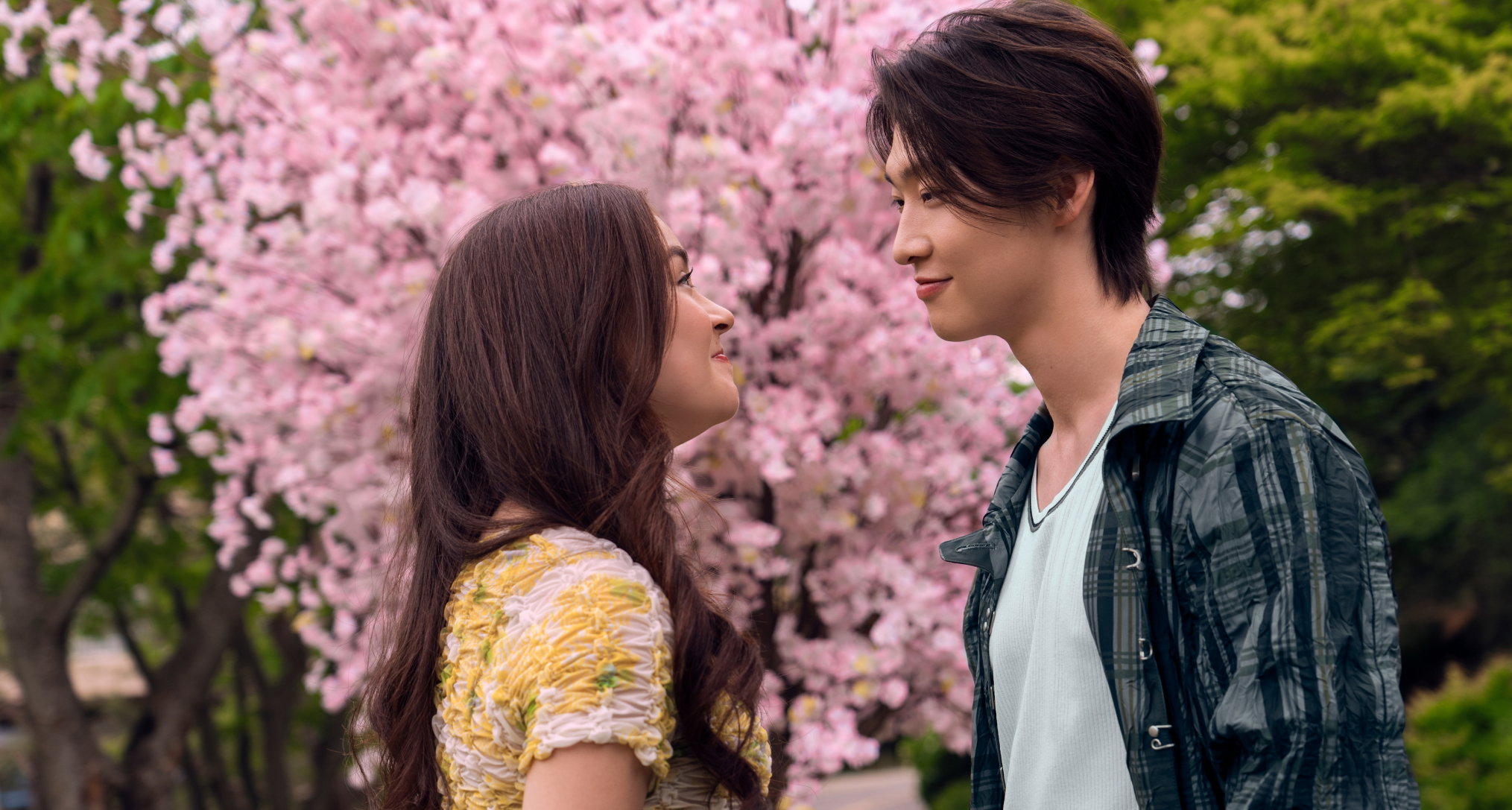 anna cathcart as kitty smiling and looking into tk's eyes outside standing in front of a cherry blossom in xo kitty season 3