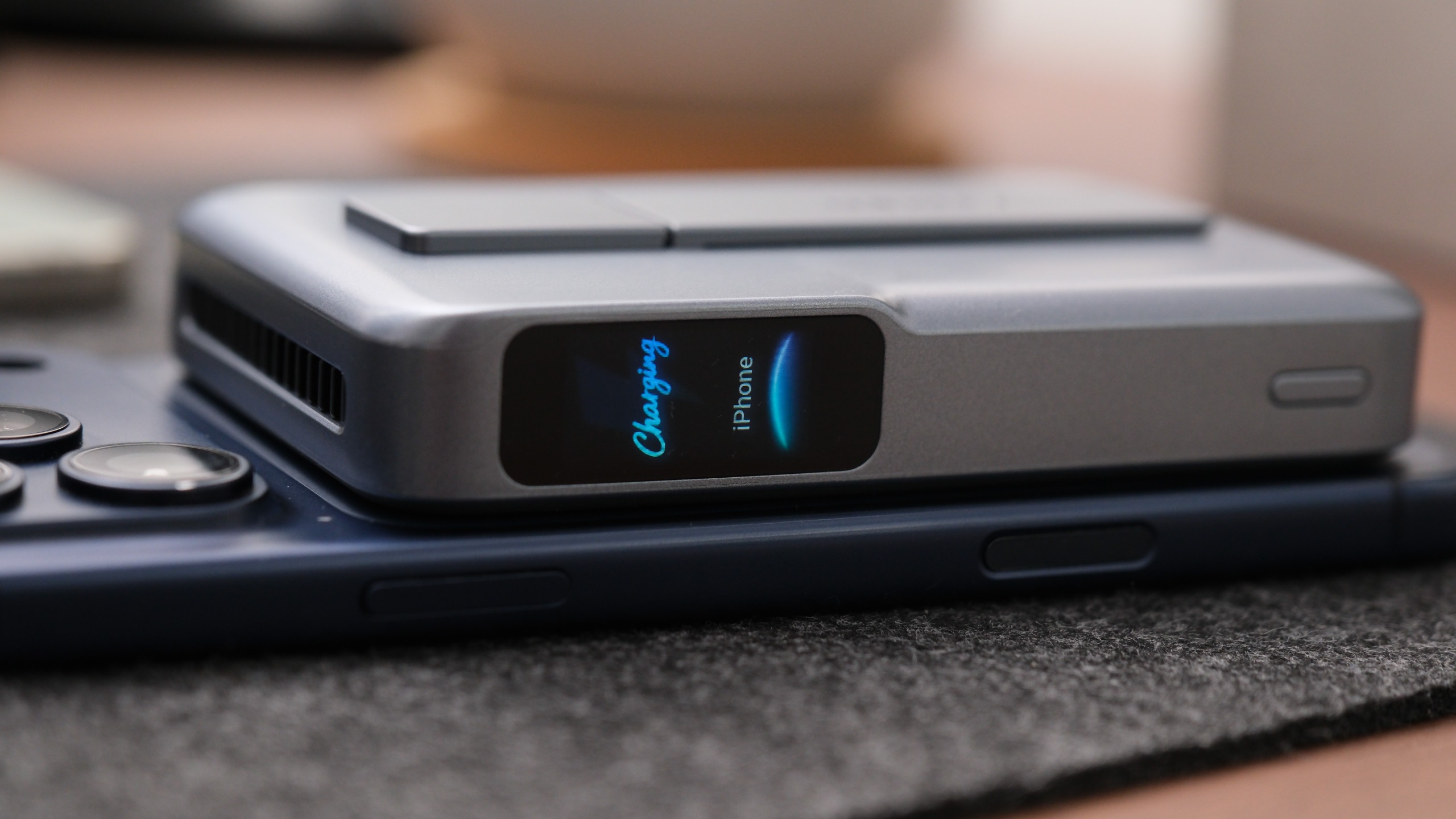 Side view of the Anker MagGo Power Bank 2 Pro resting on a smartphone, with its display showing that an iPhone is charging.