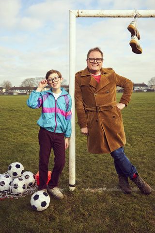 Alan Carr and Oliver Savell stand by a football goal in Changing Ends