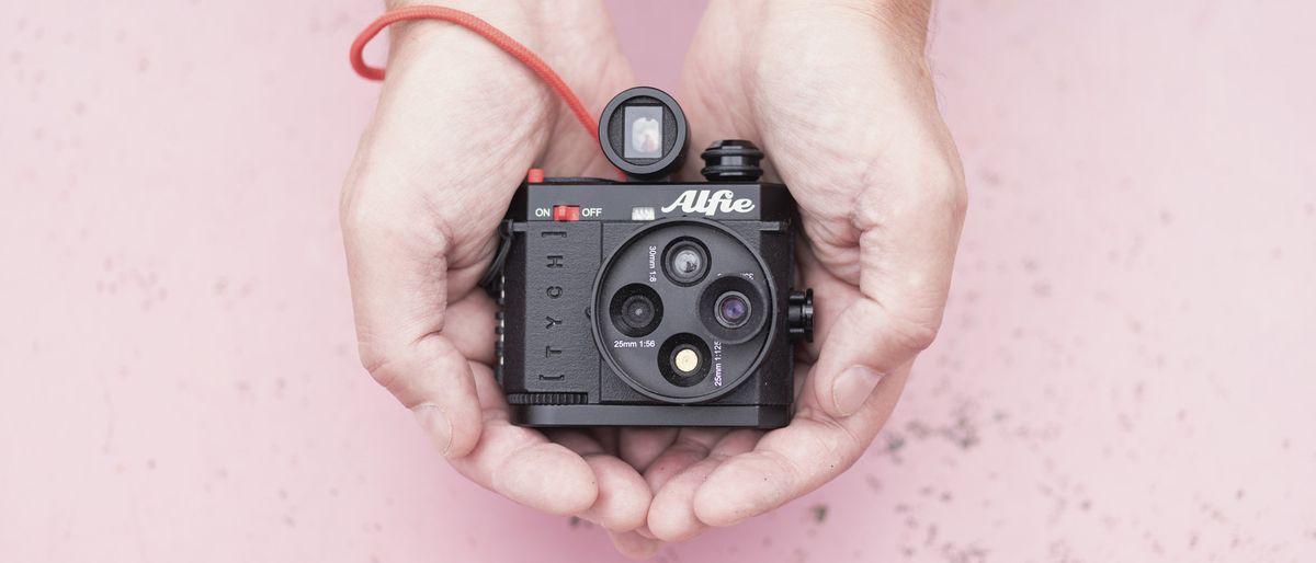 Alfie Tych camera in the hands with pink background