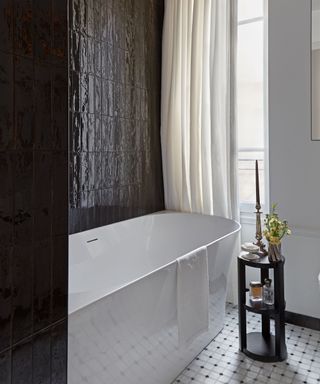 bathroom with black tiles and freestanding bath with tiled floor