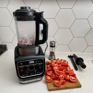Ninja Foodi HB150UK Blender and Soup Maker next to chopped tomatoes on wooden chopping board