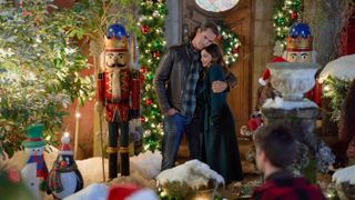 Victor Webster and Erica Cerra standing in a yard in Mystery on Mistletoe Lane