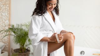 woman dry brushing legs in bathroom