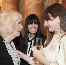 Queen Camilla wearing a black-and-white dress talking to Emily Mortimer who is holding a champagne glass 