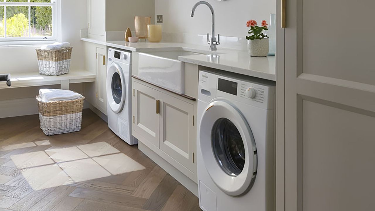 Utility room with cream shaker cupboards, washing machine and herringbone flooring.