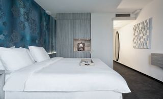 Room with white linen and walls, feature wall with patterned blue wallpaper