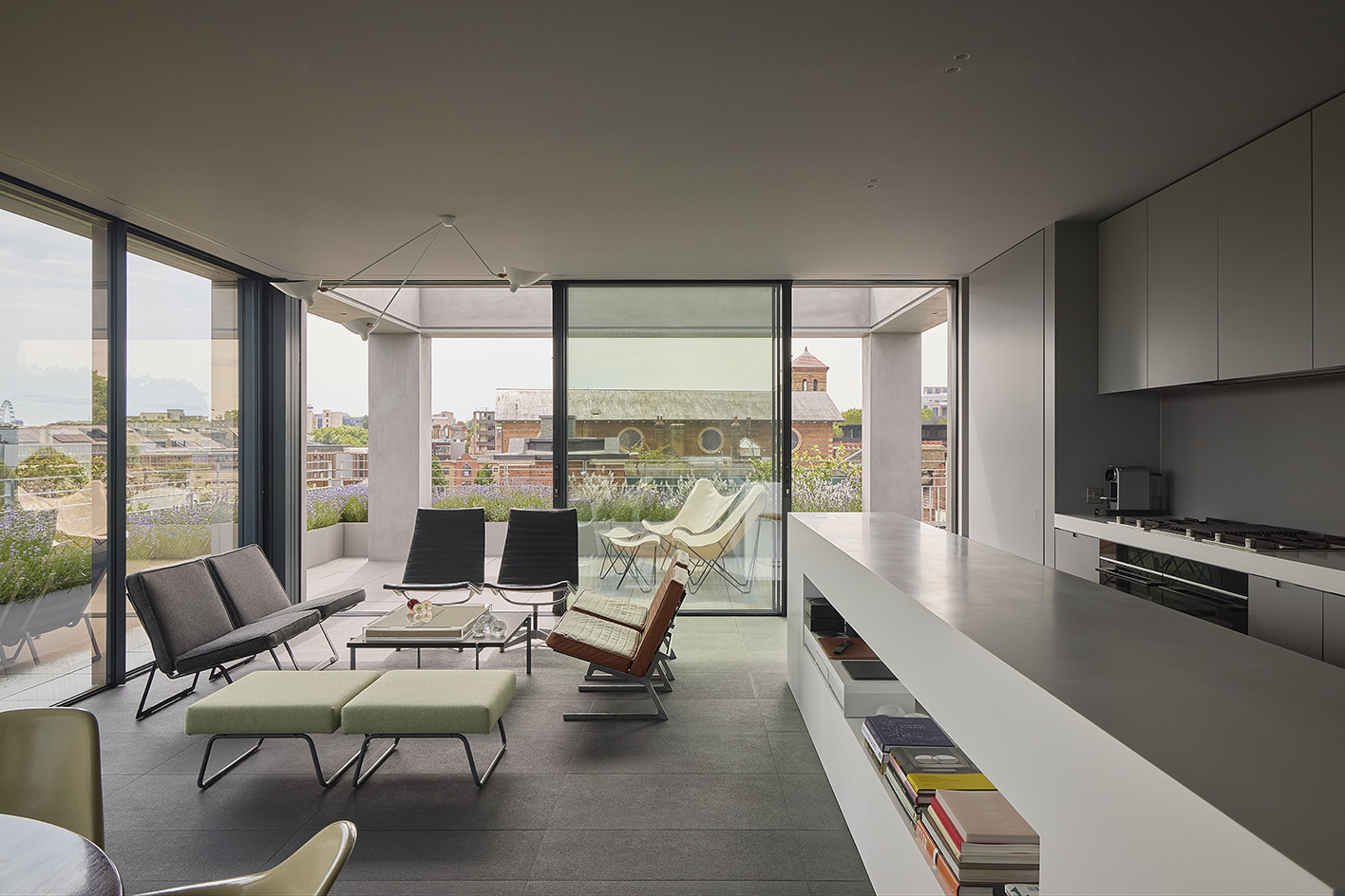 Clerkenwell Rooftop apartment in London, showing minimalist concrete and large openings with terrace and views out to urban views with green