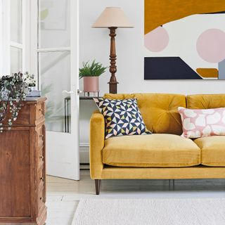 living room with yellow sofa white walls and floor abstract art painting hung on wall