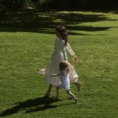 Meghan Markle and Princess Lilibet running through the backyard of their house in flowy dresses