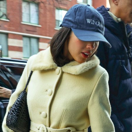 Olivia Rodrigo wearing a baseball cap, yellow coat, bootcut jeans, and ballet pumps in NYC