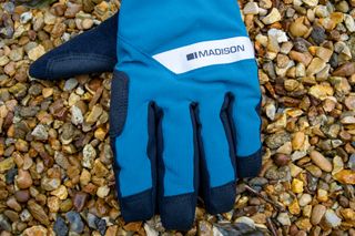 A pair of blue Madison DTE waterproof gloves on gravel