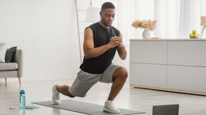 A man performing a lunge as part of a home workout