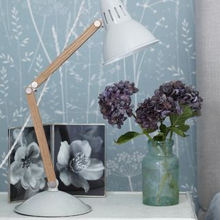bedroom with wallpaper and lamp near flower pot and frame