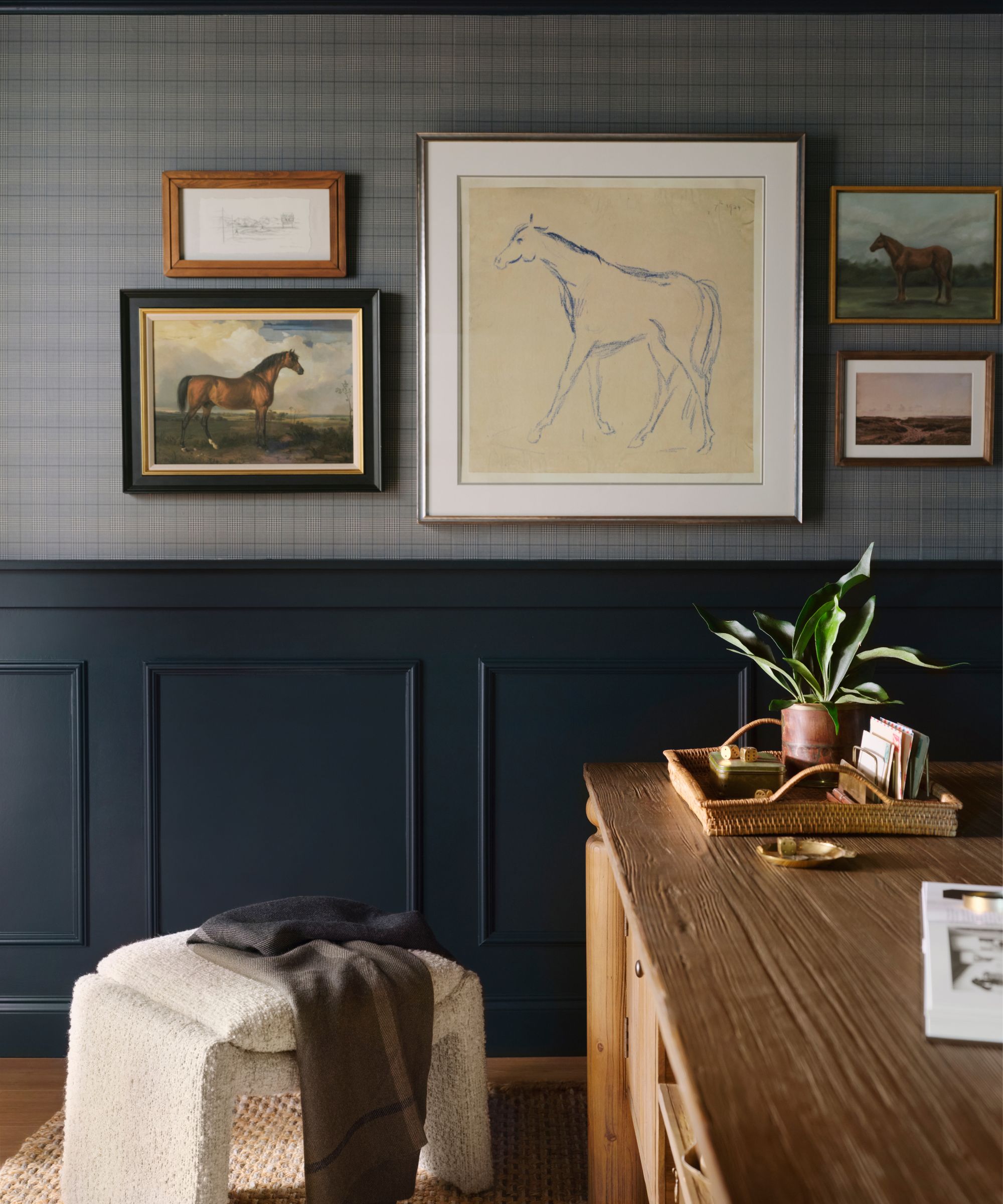 Wall with plaid wallpaper, navy blue panelling, horse art and wood desk