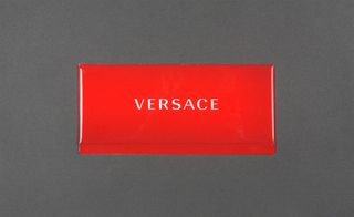 Front view of Versace's red invitation pictured against a grey background
