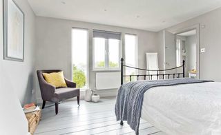 Floor-to-ceiling glazing maximises views in an all-white loft conversion with purple chairs and a purple blind