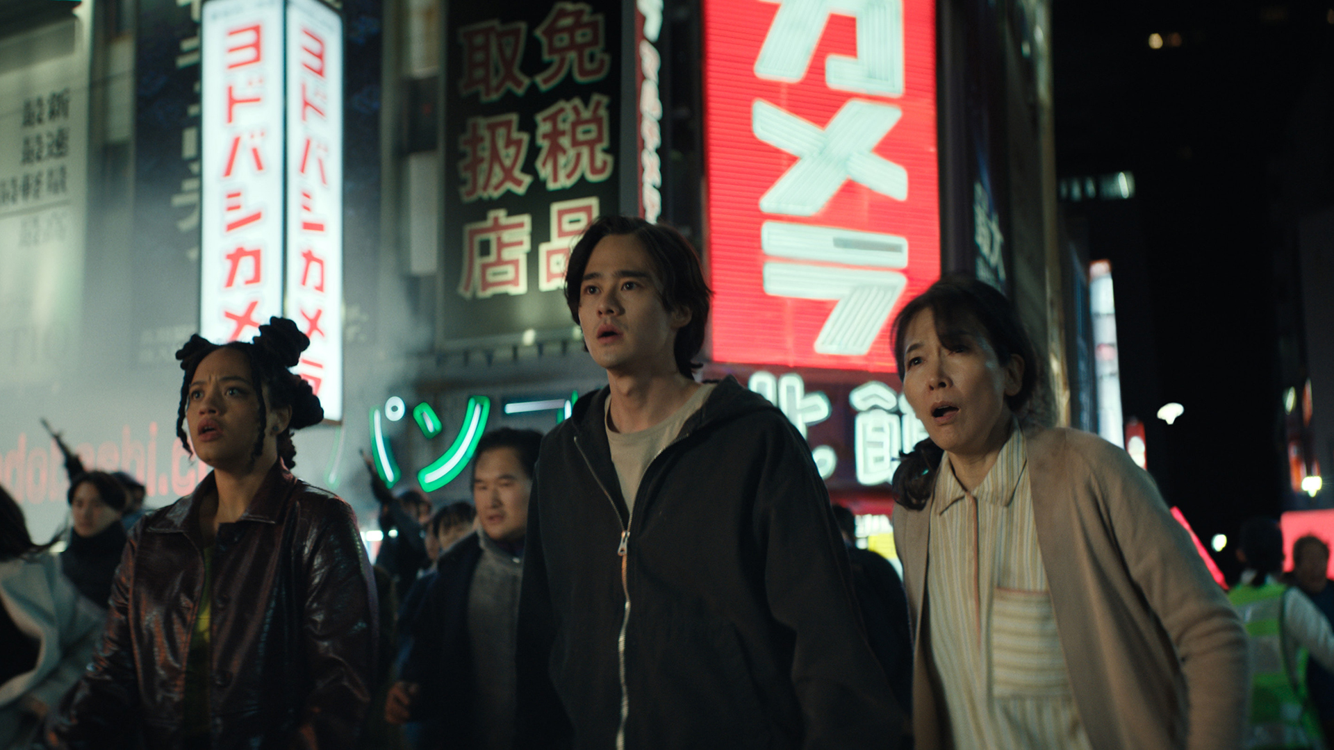 May and Kentaro standing on a crowded street at night and looking shocked in Monarch: Legacy of Monsters season 2 episode 6