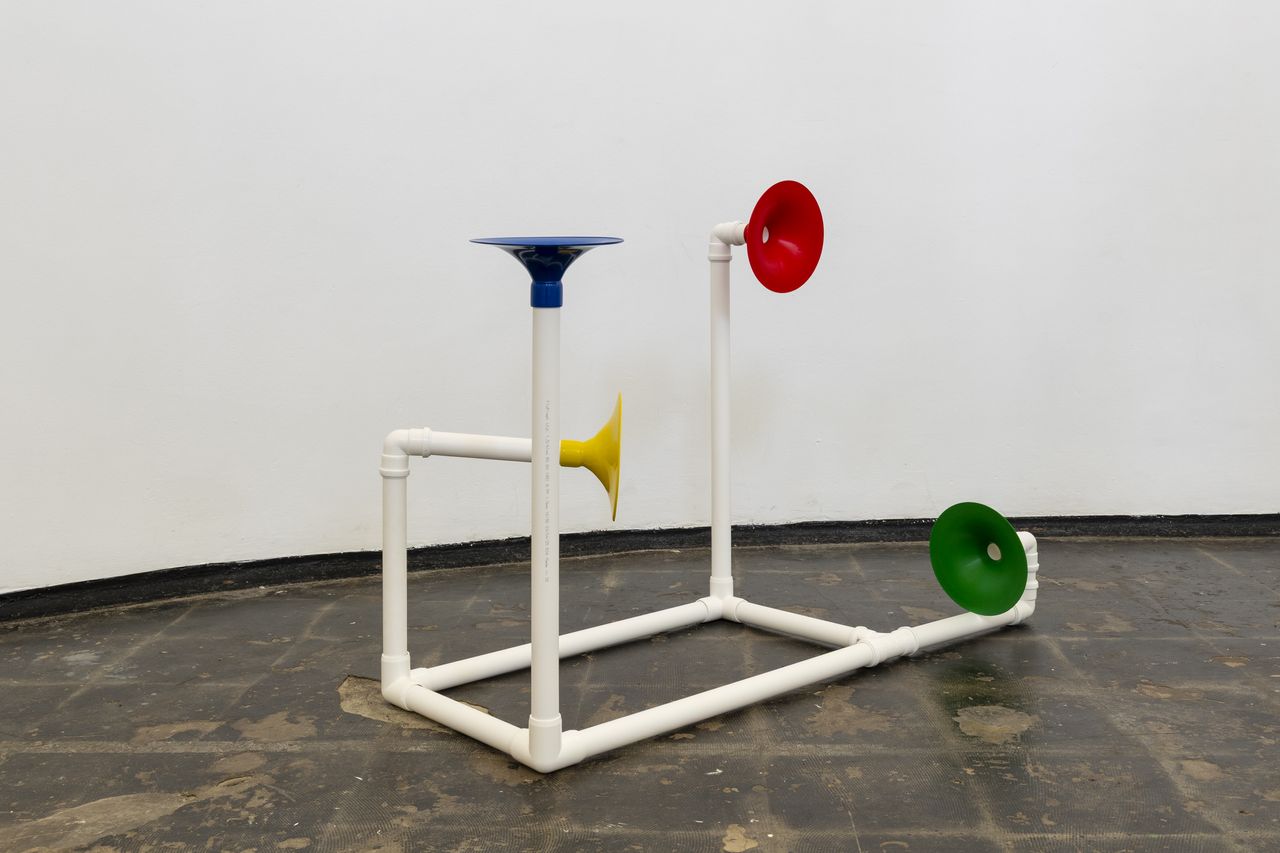 Installation in a former church made out of white pipes and colourful funnels