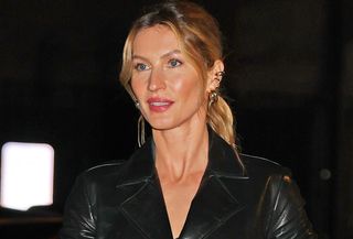 Gisele Bundchen wearing a black trench coat with knee-high boots in New York City during NYFW.
