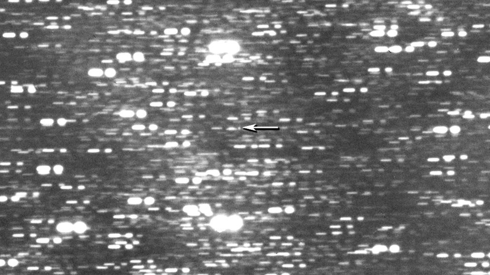 Photo of a blurry starscape with an arrow pointing out the location of the interstellar object 3I/ATLAS 