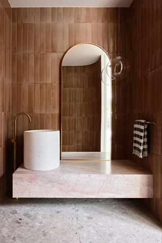 a bathroom with brown tiles and a low vanity