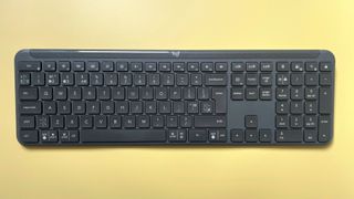 The Logitech Signature Slim K950 wireless keyboard against a yellow background.
