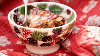 ceramic blackberry bowl on a red tablecloth with a hearty autumn pudding