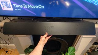 The Amazon Fire TV Soundbar Plus under an Amazon TV, in a man's hand.