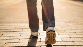 Lower half of woman's legs wearing jeans and trainers walking away from the camera