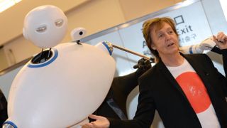 Paul McCartney greets fans and journalists upon his arrival with a robot (L) at the Haneda airport in Tokyo on May 15, 2014