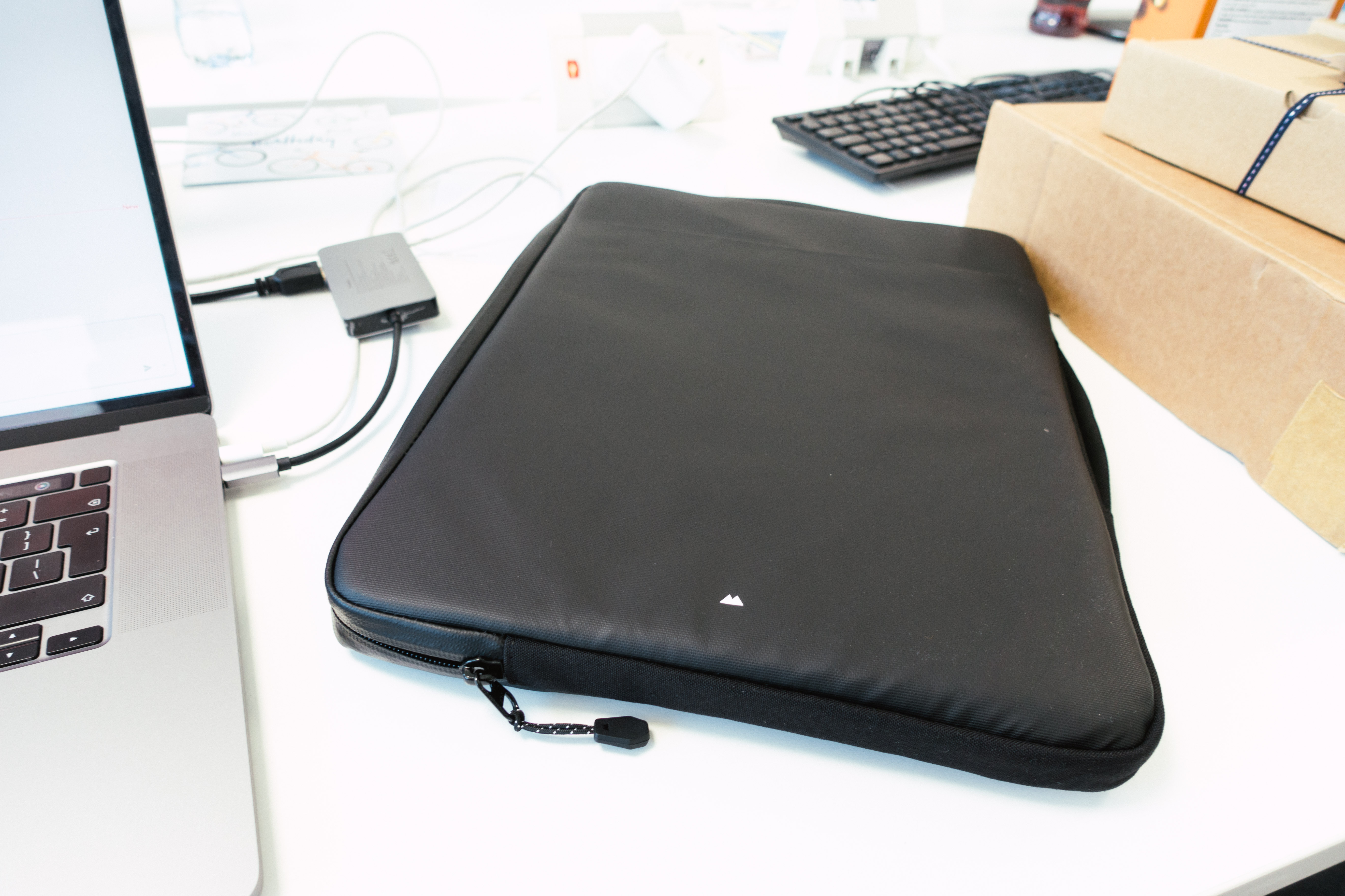 A black laptop case sits on a white desktop next to a keyboard