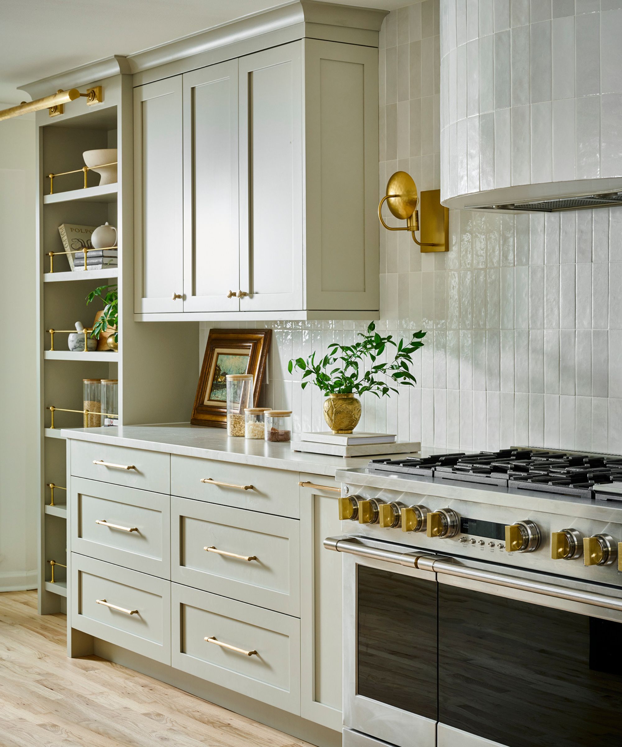 A pale green kitchen with a white tile backsplash and smart storage