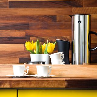 walnut coloured worktop cups and potted yellow flower