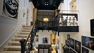 Black staircase leads from the living room and has celebrity pictures lining the walls