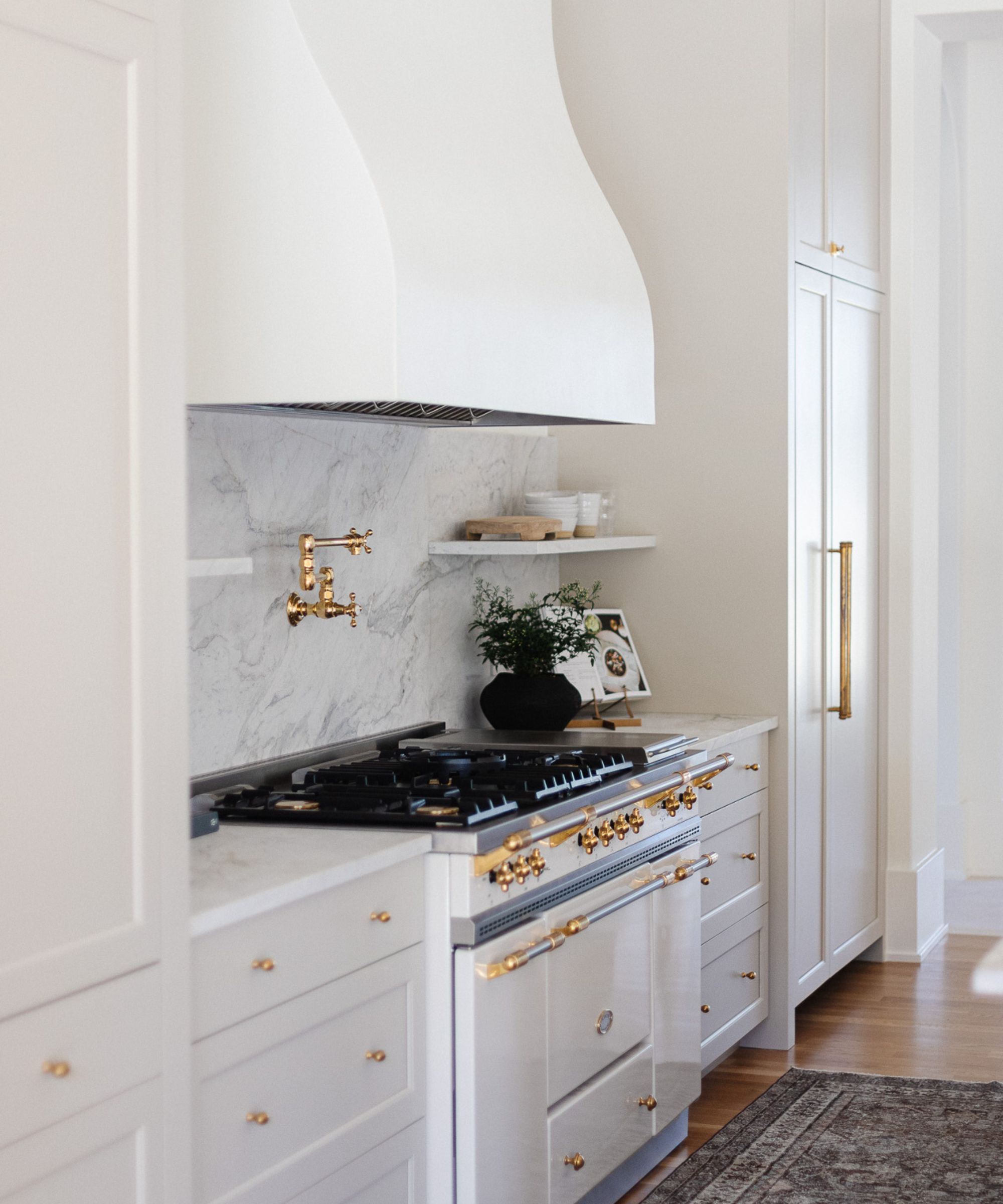 white kitchen cabinets with brass fixtures, marble backsplash