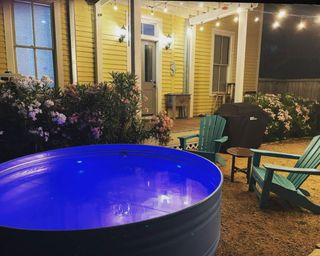 stock tank pool in front of a yellow clapboard house